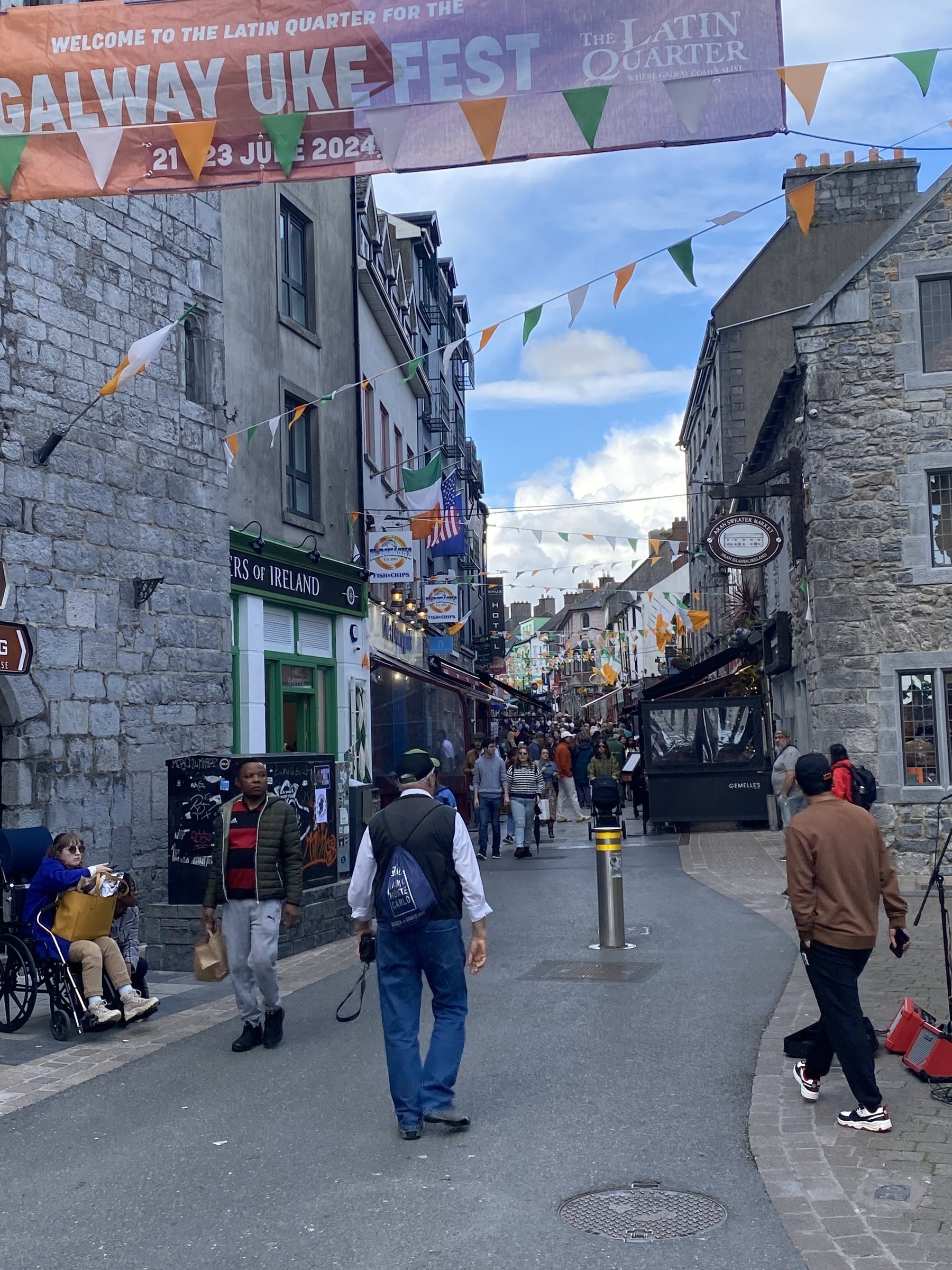 Colorful bunting and a Galway Uke Fest banner span a lively pedestrian street in Galway's Latin Quarter.