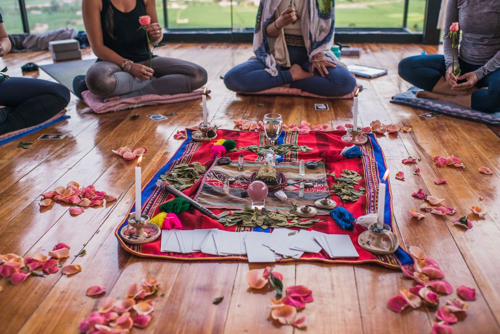 Participants sit in a circle around a traditional Peruvian altar with candles, crystals, and coca leaves during a ceremony in the Sacred Valley.
